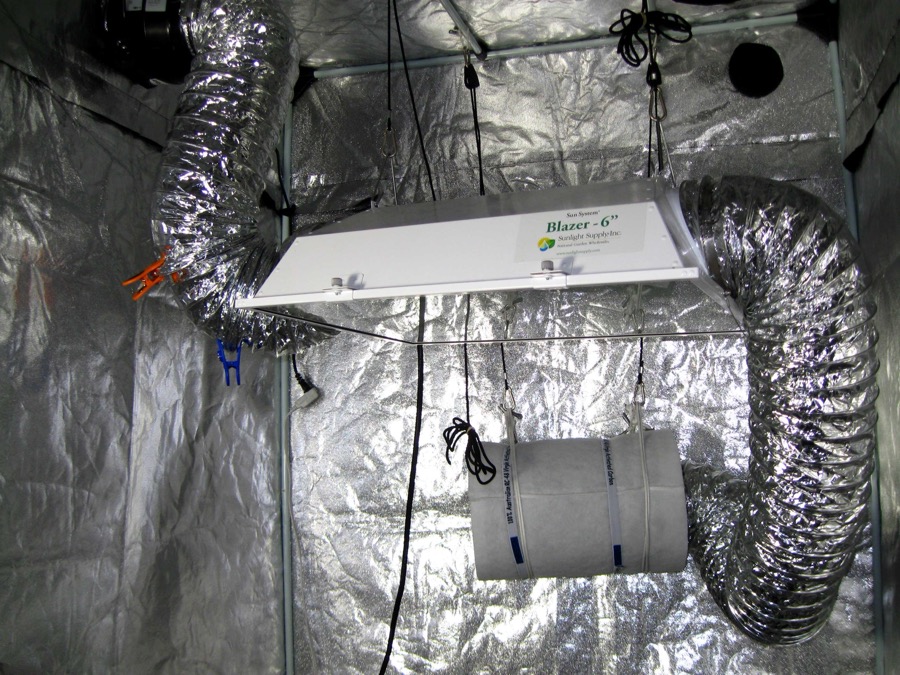 Inside a grow tent showing ducting, a carbon filter, and an exhaust fan setup